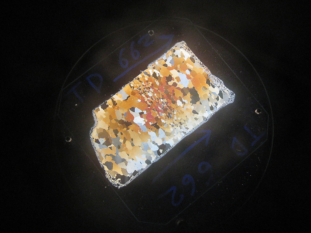 Lame mince réalisée au microtome dans une carotte de glace antarctique. Observée en lumière polarisée/analysée dans une chambre froide (-15°C) du Laboratoire de Glaciologie et Géophysique de l'Environnement (LGGE). La couleur des cristaux dépend de leur orientation.