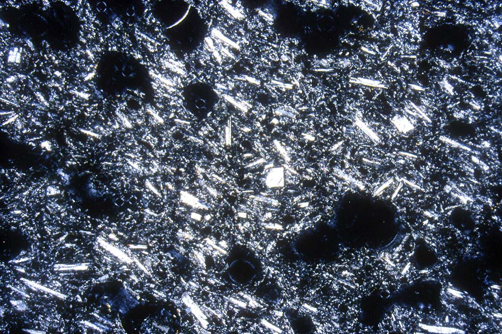 Andesite : texture microlithique avec quelques phénocristaux de plagioclases. Les taches noires correspondent à des bulles.