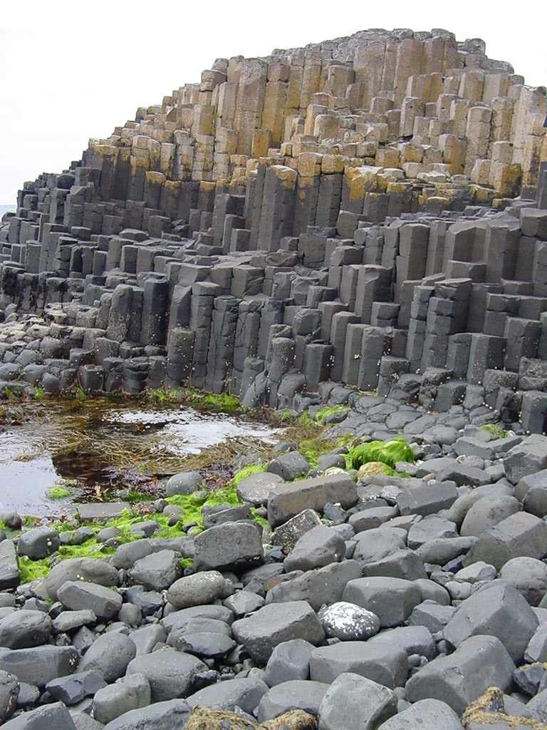 La Chaussée des Géants est la plus spectaculaire d'une série de formations  géologiques similaires, situées tout le long de la côte Nord de l'Antrim.  Elles sont nées lors d'une gigantesque éruption volcanique, qui s'est  produite il y a 60 millions d'années et a affecté le Nord-est de l'Irlande,  mais aussi l'Ouest de l'écosse on retrouve des formations de ce type aux  grottes de Fingal, sur l'île de Staffa, les îles Féroé, l'Islande et le  Groenland.
<BR>
<A HREF='https://phototheque.enseigne.ac-lyon.fr/photossql/GoogleEarth/antrim_chaussee.kmz'>
<IMG SRC='googleearth.gif' BORDER=0>
</A>