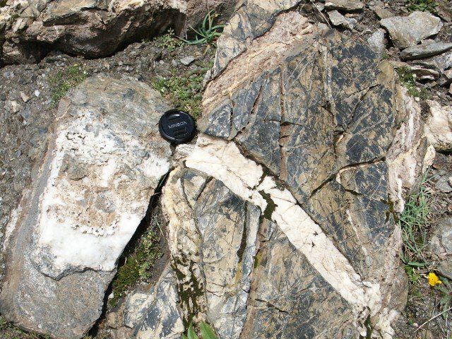 Ophicalcite. Veines de calcite cristallisée dans des fractures au sein de la péridotite serpentinisée.