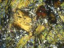 Sur cette photo de roche métamorphique, on voit des disthènes (neosilicate d'alumine, minéral marqueur de hautes pressions). Certains sont rougeâtres (en haut à droite) et un autre est beaucoup plus gros, jaune (rectangle oblique à mi-photo). Les minéraux rougeâtres sont antérieurs à la déformation (ante S2), le minéral jaunâtre accompagne la déformation (syn S2 - phénomène d'hélicitisme). [30836 views]
