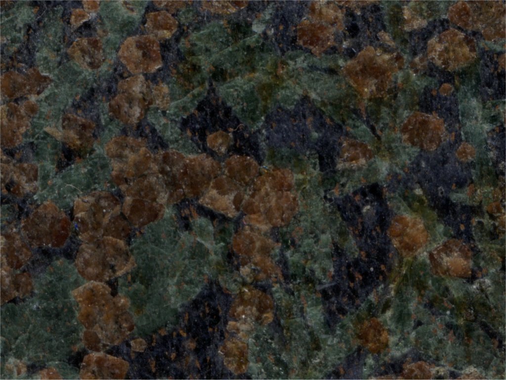 Echantillon d'éclogite du Mont Viso, surface polie scannée. On distingue des cristaux de grenat (rouge), de jadéite (vert) et de glaucophane (bleu nuit).