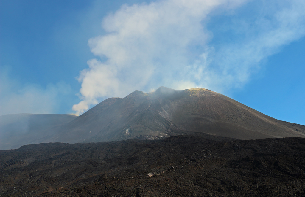 L'Etna est un volcan italien situé en Sicile, à proximité de la ville de Catane. Il y a dix volcans en activité sur le territoire italien. Seuls le Stromboli et l'Etna ont une activité assez continuelle, les autres étant néanmoins susceptibles d'entrer en activité à moyen terme. Ici, sur l'Etna nous voyons au premier plan la coulée du printemps 2017 et par endroits des petites fumerolles.