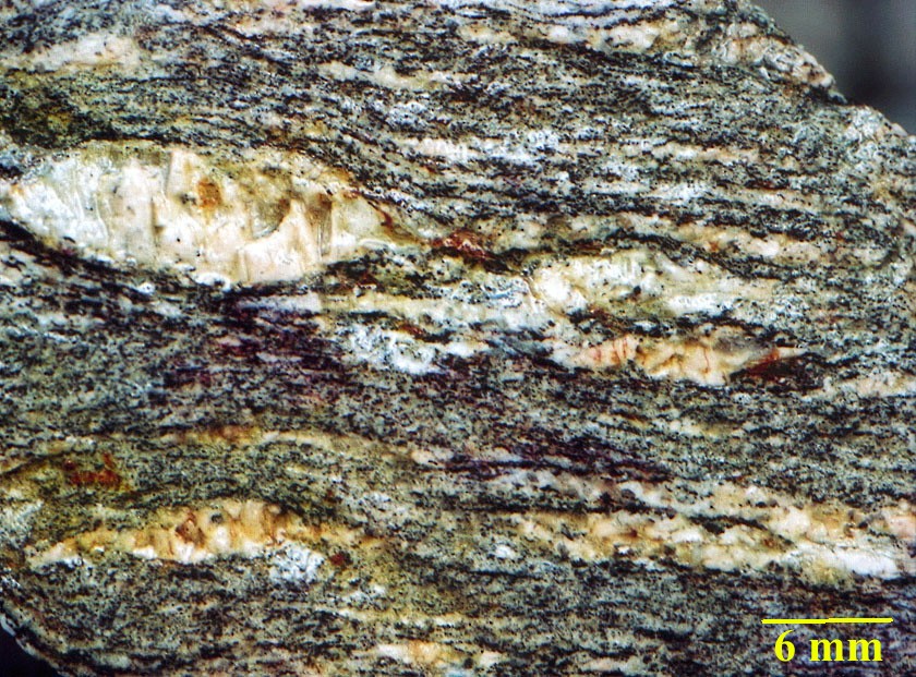 Gneiss du Velay. Orthogneiss provenant du métamorphisme de granites monzonitiques porphyroïdes (528 Ma, Cambrien supérieur). Ils constituent le toit du granite du Velay. Ce sont des gneiss oeillés, foliés à porphyroclastes de feldspath potassique, quartz, biotite, plagioclases, feldspath potassique, sillimanite. Les porphyroclastes sont des phénocristaux magmatiques hérités du granite. De la muscovite tardive apparaît sur les feldspaths potassiques. <a href='http://svt.enseigne.ac-lyon.fr/spip/spip.php?article153' target='_blank'>Page liée</a>.<br />  Mots clefs: gneiss oeillés - métamorphisme - felspath.
