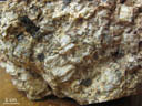 Granite porphyroïde à cordiérite du Rouet (302 Ma). Dans ce granite porphyroïde à feldspaths potassiques centimétriques à clivages bien marqués et à quartz gris globuleux, la cordiérite se présente en cristaux prismatiques vert sombre. On pourra en distinguer une section longitudinale et plusieurs sections transversales subhexagonales présentant des clivages.<br />\nLe granite du Rouet est un granite alumineux  à cordiérite, et à enclaves sombres. Il est intrusif dans le cœur de l'antiforme plurikilométrique du Rouet où il recoupe des gneiss migmatitiques et la tonalite de Prignonet (feuille Fréjus-Cannes à 1/50 000). [21967 views]
