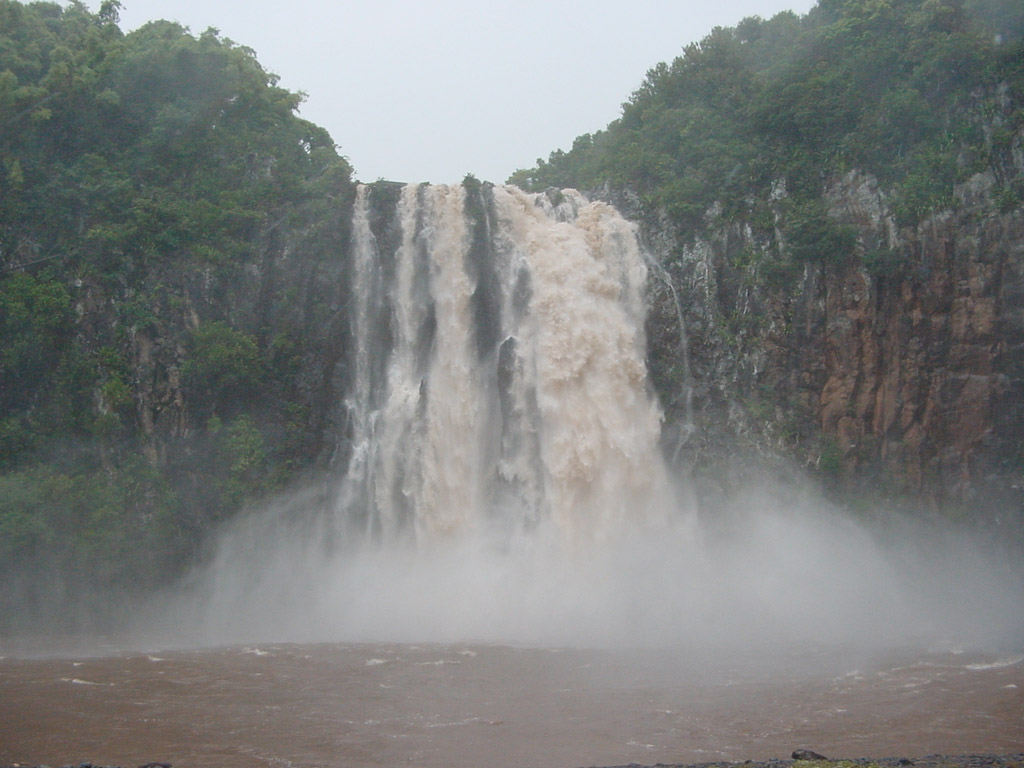 La rivière Sainte Suzanne draine le nord-est de l'île de la Réunion. Lors de cette pré-alerte cyclonique, les pluies abondantes accroissent le débit de la rivière et le transport des particules sédimentaires : on voit l'eau de la cascade Niagara teintée d'ocre par les particules argileuses transportées.