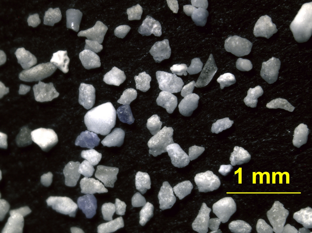 Sable de plage, à grain fin (<< au mm) formé essentiellement de grains de quartz.<br />    Photographie réalisée avec une caméra numérique sur l'oculaire d'une loupe.