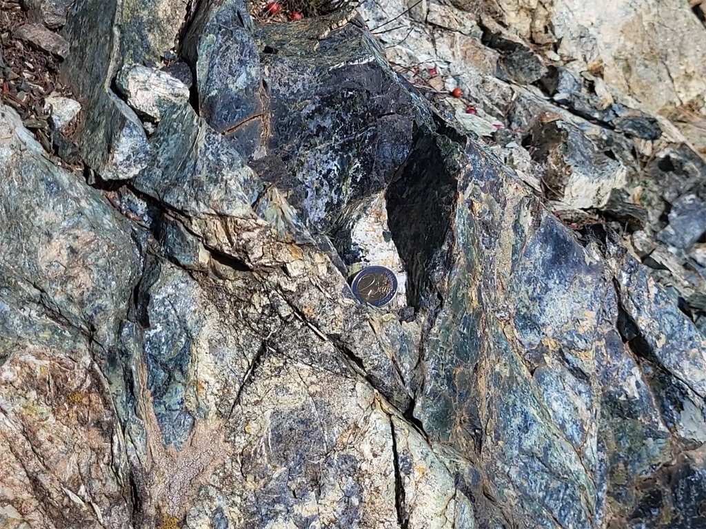 Affleurement de serpentinite. Il s’agit de phyllosilicates résultant de l’hydratation des olivines (et accessoirement des pyroxènes) des péridotites. Ce sont donc les produits du métamorphisme du manteau. Les formes les plus courantes de serpentinites sont vertes à blanches ou jaunâtre, avec souvent des reflets bleutés. Elles tirent leur nom de leur aspect semblable à celui d'écailles et une sensation particulière au toucher, qui peut évoquer la peau d'un serpent. Ces roches se trouvent généralement dans des chaines de montagnes, anciennes ou récentes, qui ont amené à proximité de la surface des parties du manteau terrestre.<br />
<a href= 'https://phototheque.enseigne.ac-lyon.fr/photossql/photos.php?RollID=images&FrameID=serpentinite_gavignano1'>Vue d’ensemble de l’affleurement</a> – <a href='https://phototheque.enseigne.ac-lyon.fr/photossql/photos.php?RollID=images&FrameID=serpentinite_gavignano2'> Vue rapprochée 1</a> – Vue rapprochée 2 – <a href='https://phototheque.enseigne.ac-lyon.fr/photossql/photos.php?RollID=images&FrameID=serpentinite_gavignano4'> Échantillon 1</a> – <a href='https://phototheque.enseigne.ac-lyon.fr/photossql/photos.php?RollID=images&FrameID=serpentinite_gavignano5'> Échantillon 2</a>
