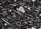 La photographie réalisée au microscope (G=200 x) montre la « pâte » gris bleutée du trachyte. Celle-ci comporte de nombreux microcristaux de feldspath, en forme de baguette. Ces cristaux semblent orientés ce qui peut signifier un écoulement de la lave figé lors du refroidissement. Entre ces microlithes, la matière noire est non cristallisée. [13290 views]