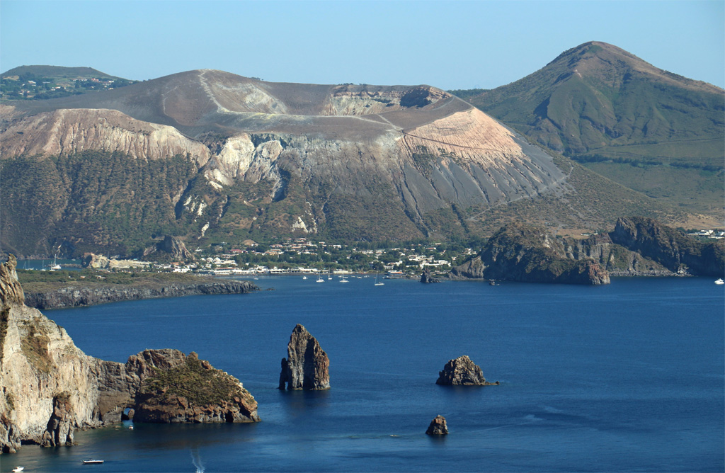 L'île de Vulcano est située au nord de la Sicile, ce lieu porte le nom de Vulcain, Dieu du feu. Vulcano définit un type de volcanisme répandu sur la planète avec de fortes explosions. La dernière a donné naissance au cône de la Fossa vu ici depuis l'île de Lipari. Nous pouvons observer les côtes escarpées avec des îlots de lave et les petites plages de sable noir. 